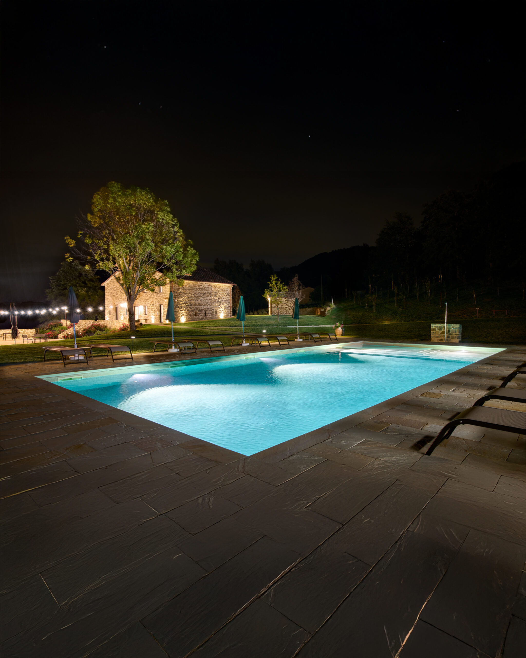 piscina illuminata di sera e vista casolare